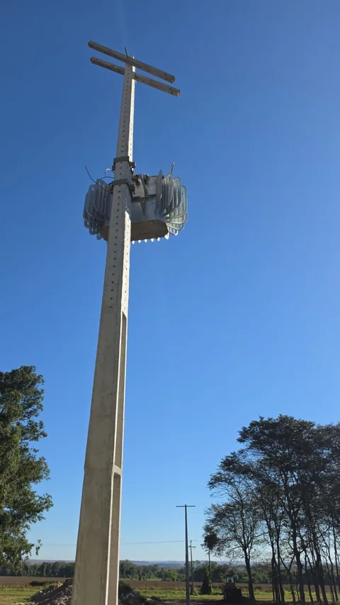 Poste com transformador e componentes de rede elétrica sob céu azul
