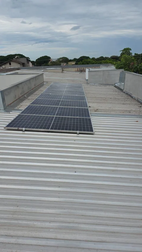 Módulos fotovoltaicos em fileiras sobre telhado metálico claro
