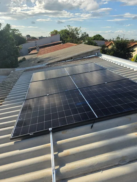 Fileiras de painéis solares sobre cobertura com casas ao redor