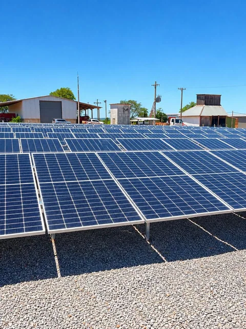 Painéis solares sobre base de brita com céu azul ao fundo